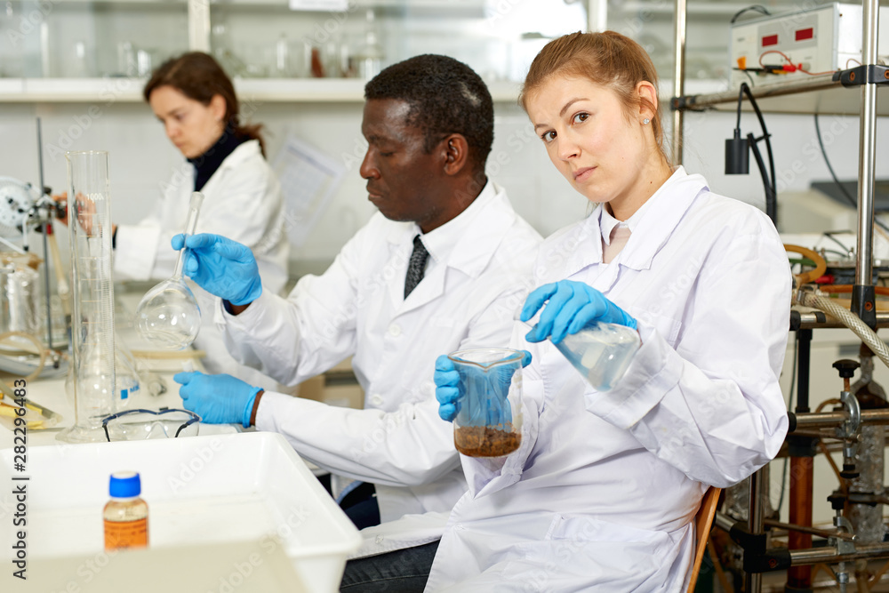 Fototapeta premium Focused woman lab technicians working with reagents and test tubes