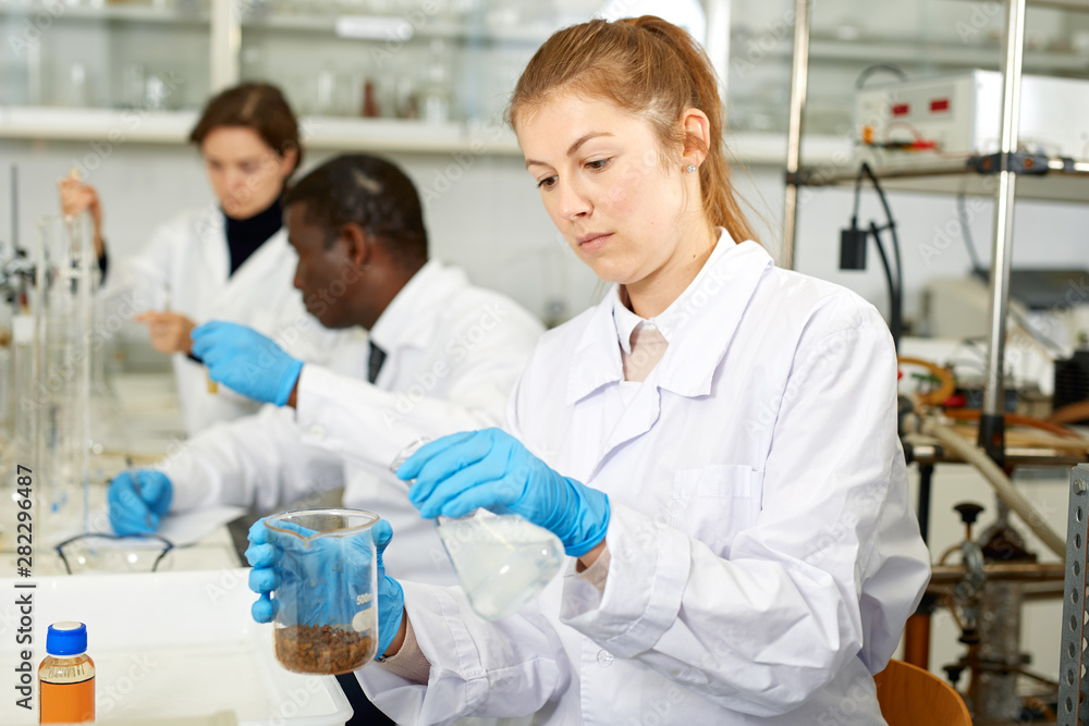 Obraz premium Serious woman lab scientist in glasses working with reagents and test tubes