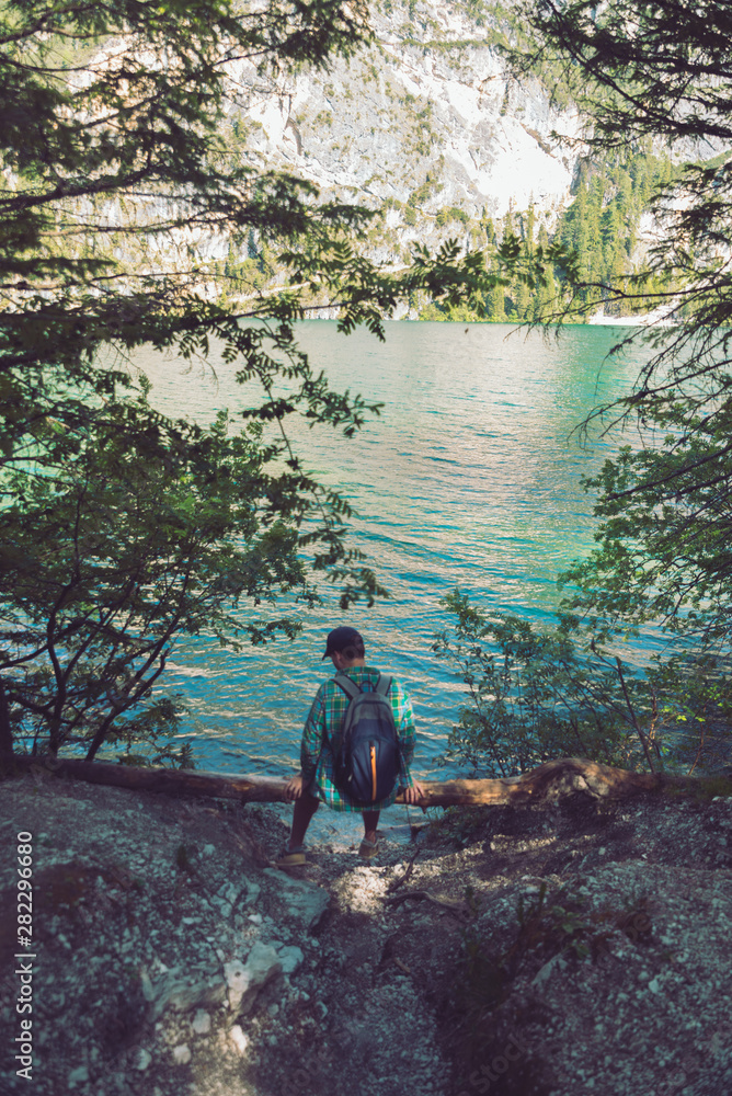 man with backpack sitting at wood log enjoying water view man with backpack sitting at wood log enjoying water view