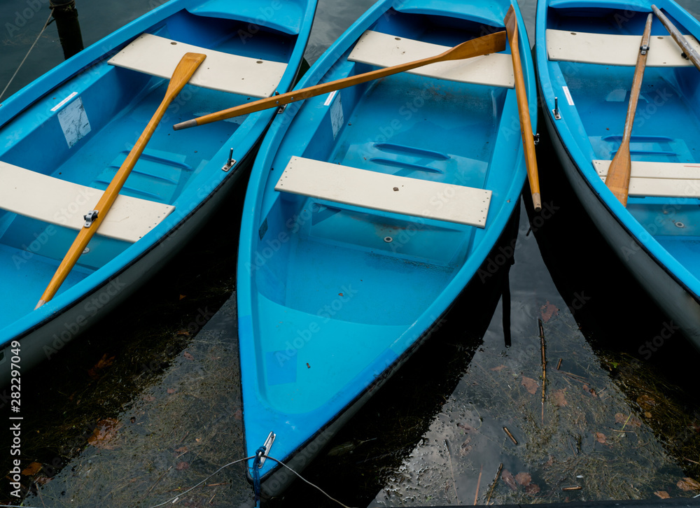 bright blue and white rowboats in dark lake water bright blue and white rowboats in dark lake water