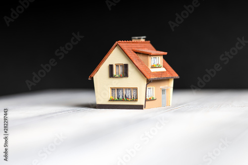 A small copy of the house is on the table on a black background.