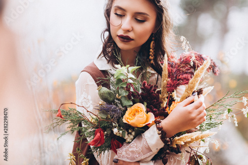 Girl in boho style on a background of autumn forest.