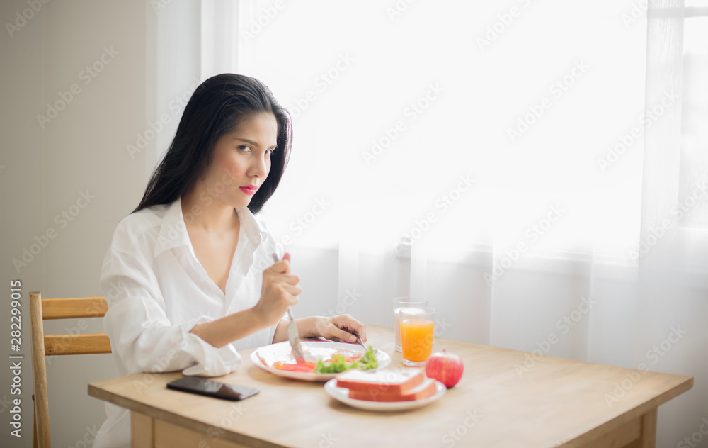 Asian women in white shirt holding a knife on the plate of breakfast, Looking at the camera with a fierce face, The importance of breakfast concept-Image
