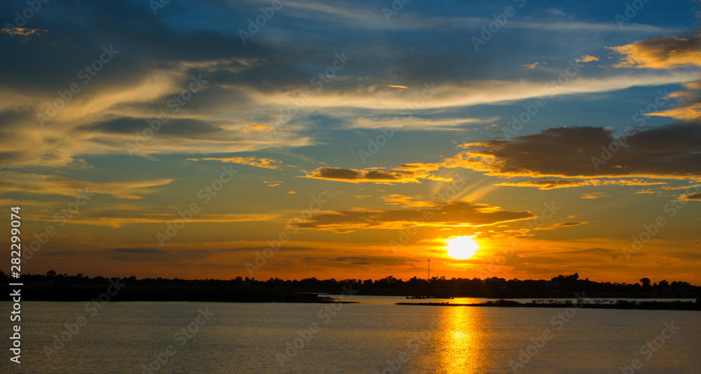 Beautiful Sunset in the sky with sky blue and orange light of the sun through the clouds in the sky, Orange and red dramatic colors over the sea. - Image