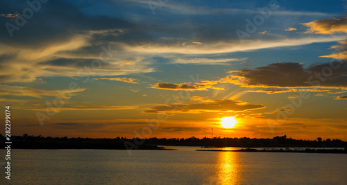 Beautiful Sunset in the sky with sky blue and orange light of the sun through the clouds in the sky  Orange and red dramatic colors over the sea. - Image