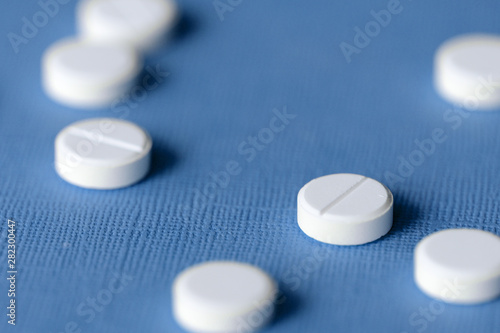 White tablets scattered on a blue background close up