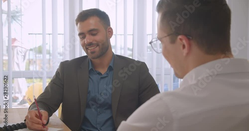 Closeup portrait of two attractive businessmen having a formal discussion in the office indoors