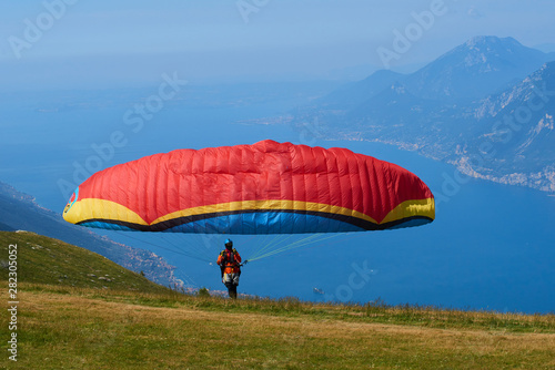 Paraglider flying over the Garda Lake (Lago di Garda or Lago Benaco). Paragliding on Monte Baldo. Panorama of the gorgeous Garda lake surrounded by mountains, Malcesine, Italy