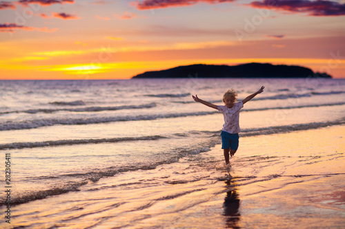Child playing on ocean beach. Kid at sunset sea. © famveldman