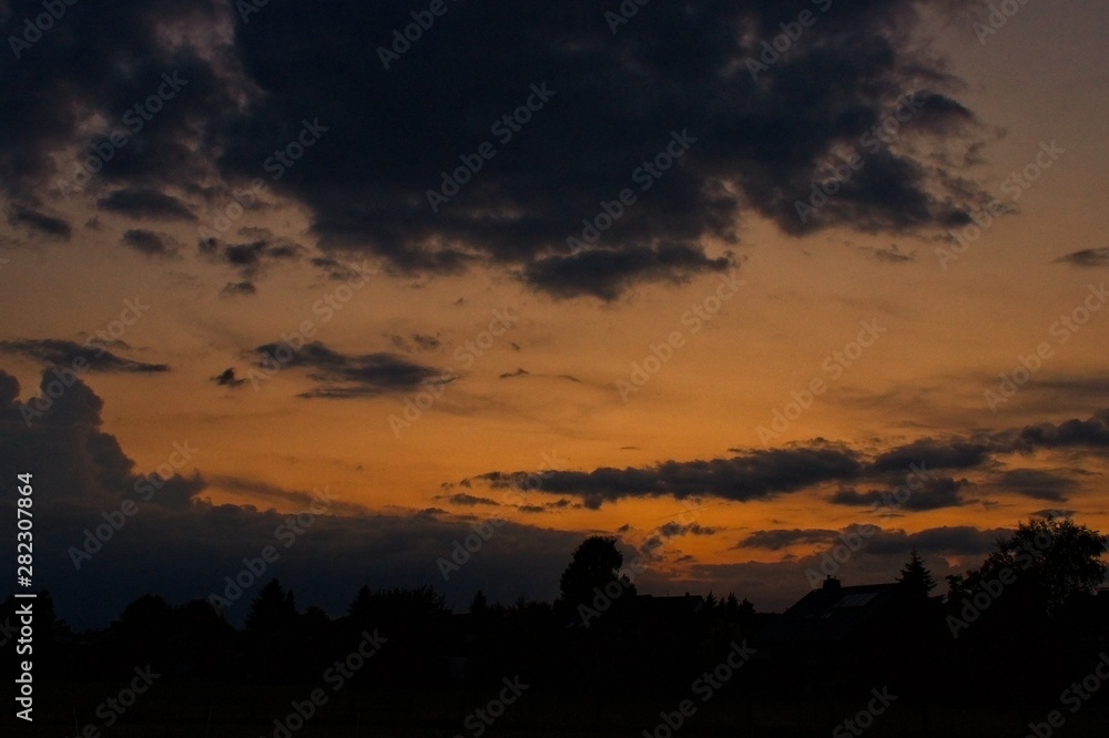 orange burning sky with silhouette of trees and houses