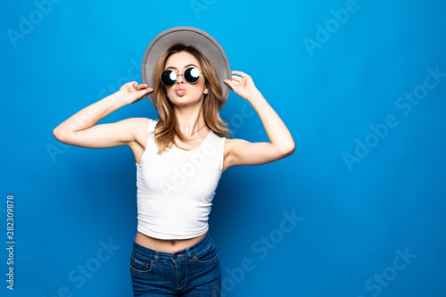 Portrait of pretty woman in sunglasses and hat over blue colorful background