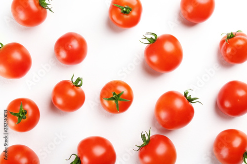 Bunch of juicy organic red cherry tomatoes scattered on isolated white background. Polished vegetables. Clean eating concept. Vegetarian diet. Copy space, flat lay, top view.