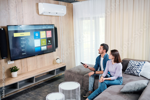 Young man and his wife choosing something to watch on digital display photo