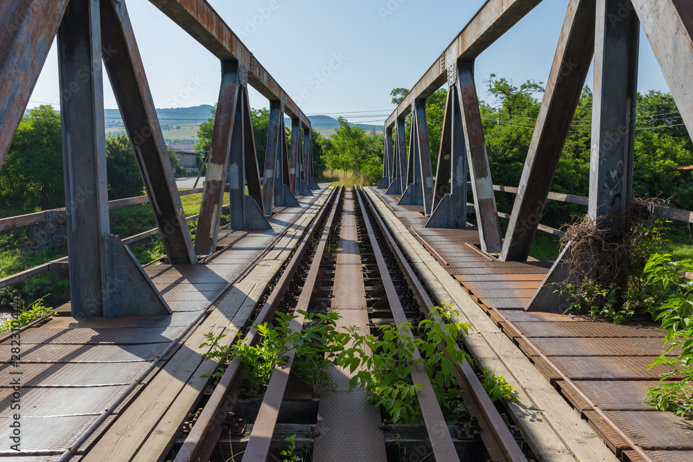 Fototapeta premium ODORHEIU SECUIESC, ROMANIA - Jul 2, 2019: Straight view over massive bridge with steel support on each side. Railways tracks. Symbol / concept for connection, communication, direct, peace, consequence