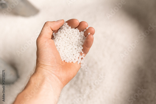 Hand of young male worker of large modern factory holding polymer granules photo