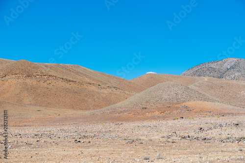 Panoramic view on the yellow field with dry grass and rock and mountains.