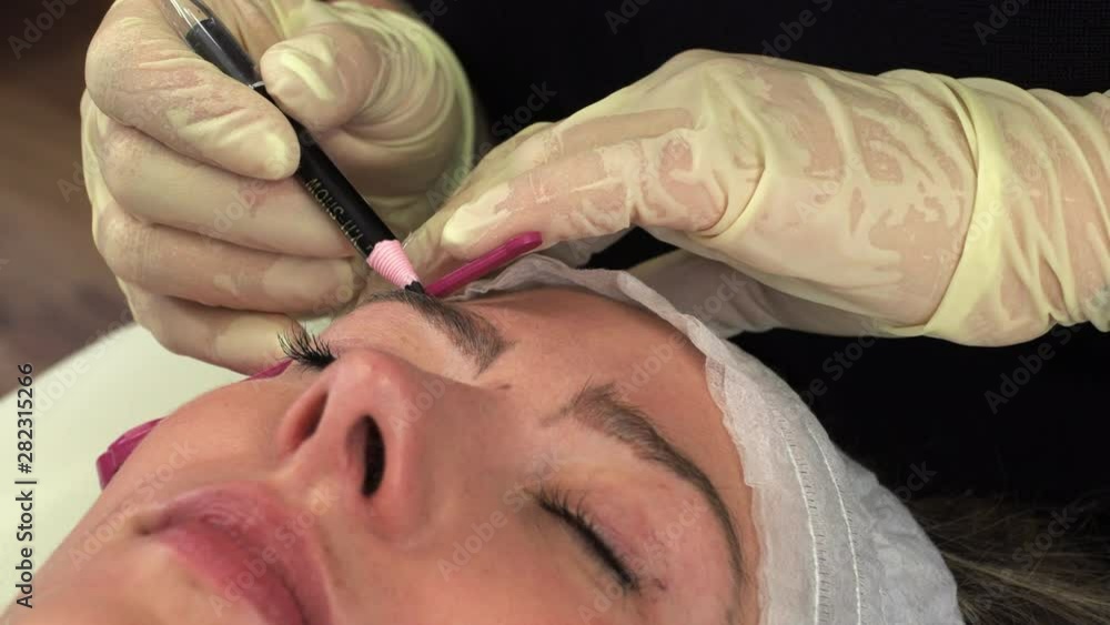Beautician makes brunette microblading procedures in a cosmetic studio Beautician makes brunette microblading procedures in a cosmetic studio