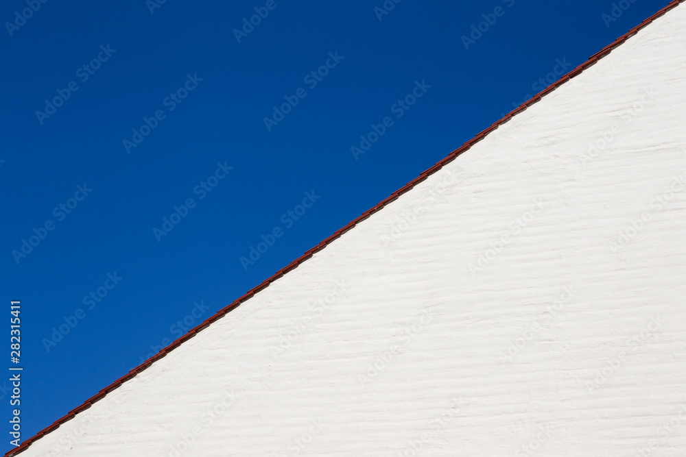 Gable wall of a white house in front of a blue sky