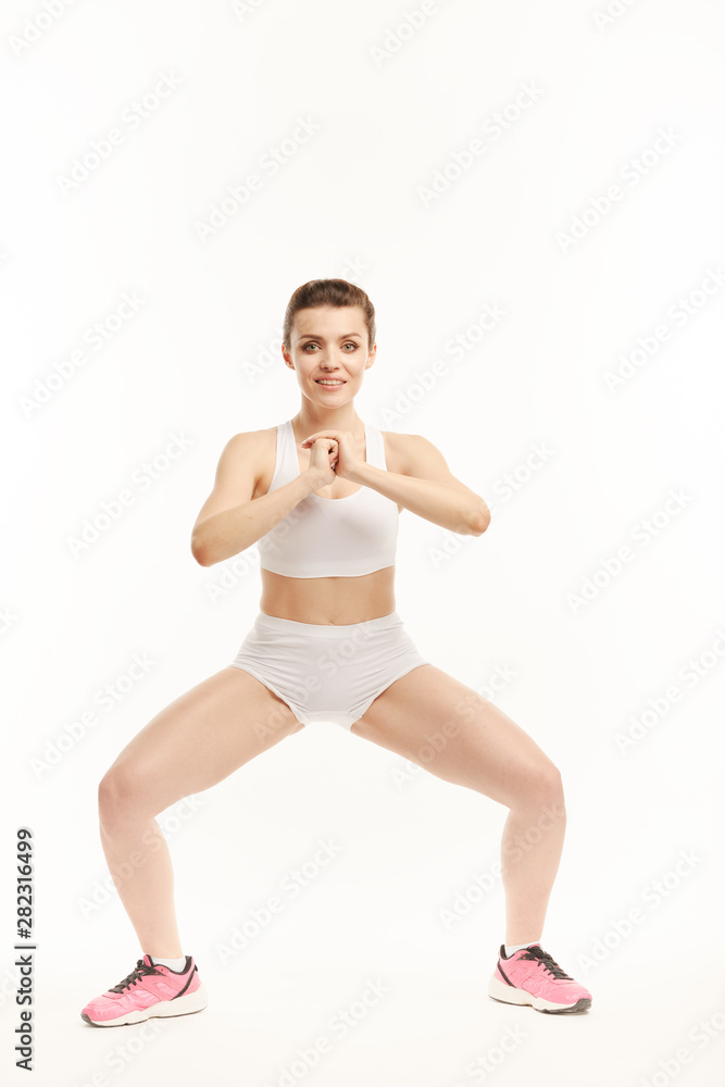 Woman in sportswear does squats in different ways. Woman in sportswear does squats in different ways.