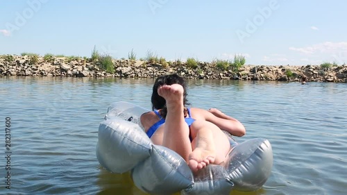 Beautiful sexy girl enjoying the sun and water girl in swimsuit floating on an air mattress on the river concept of leisure and travel