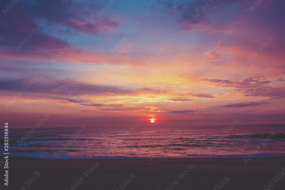 Fototapeta premium Sunset over the ocean. Sandy beach at sunset. Beautiful seashore in the evening. Porto, Portugal, Europe