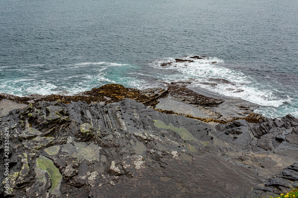 View of the limestone pavement and the sea along the coastal walk route from Doolin to the Cliffs of Moher, geosites and geopark, Wild Atlantic Way, rainy day in county Clare in Ireland