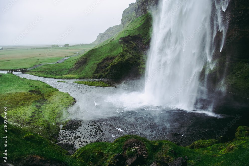 Cold pale white water of Seljalandsfoss waterfall in Iceland. Typical windy weather. Cold pale white water of Seljalandsfoss waterfall in Iceland. Typical windy weather.