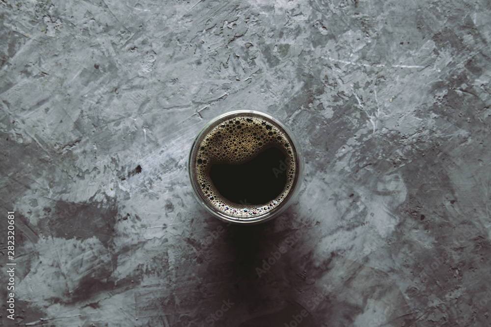 large transparent glass filled with of aromatic Turkish coffee photographed on the gray background