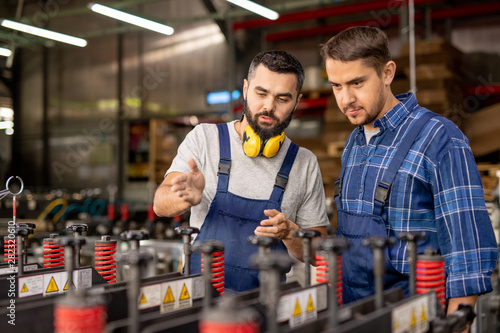 Two young men checking new industrial processing equipment