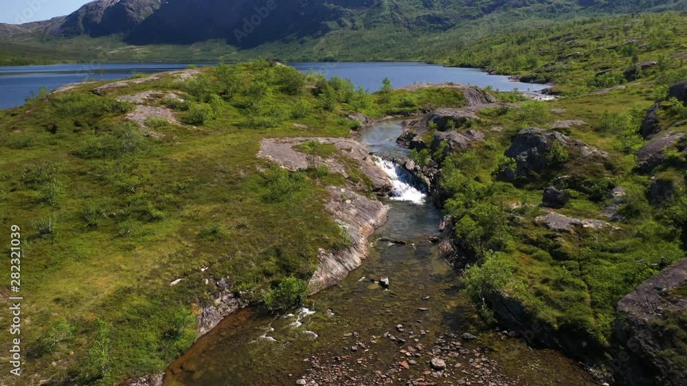 Aerial drone shot as flying over a rocky river bottom with shallow water comes from a lake in the mountains Aerial drone shot as flying over a rocky river bottom with shallow water comes from a lake in the mountains