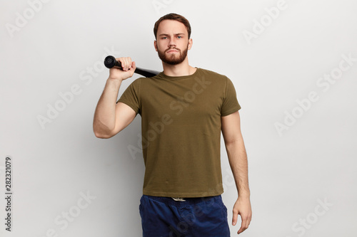 Slika na platnu serious brutal guy holding a bat behind his back, going to fight, beat somebody,