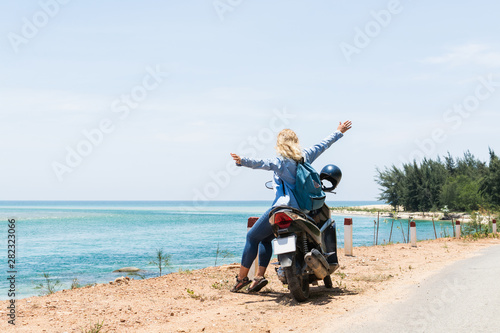 Woman riding motorcycle along the sea on the road to Hai Van pass, Vietnam