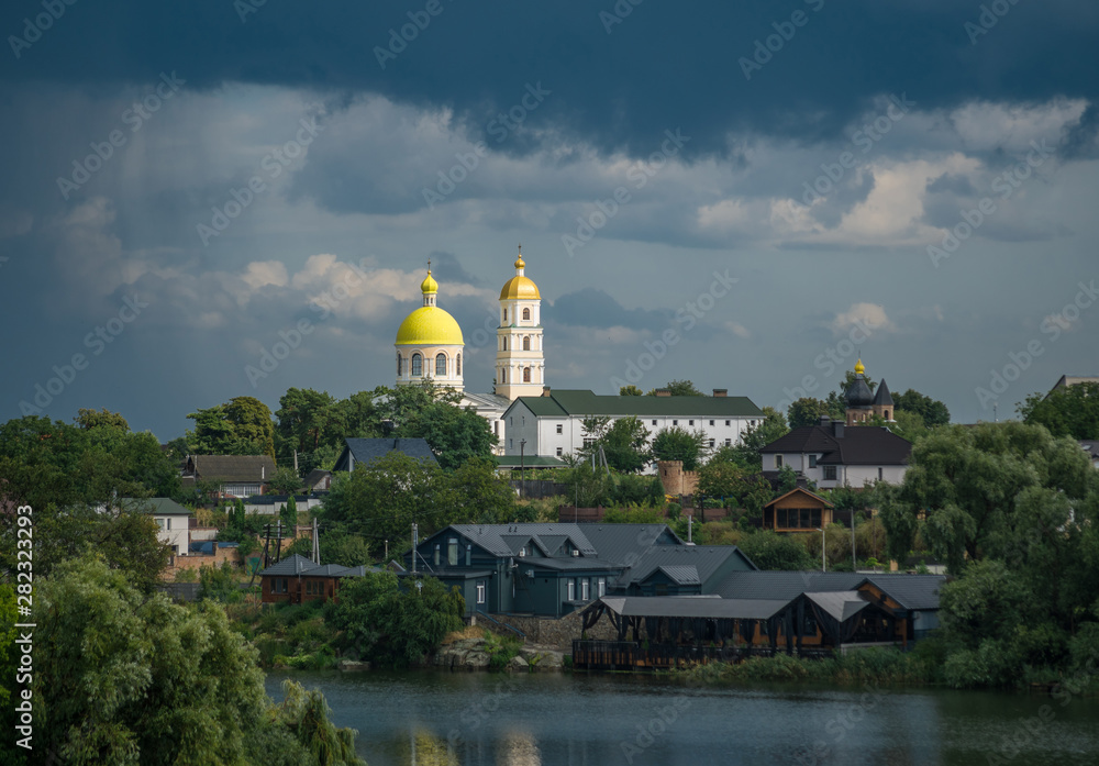Church and monastery by the river against a cloudy sky in summer after rain