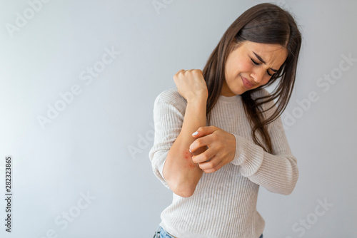Women scratch the itch with hand , Concept with Healthcare And Medicine. Woman scratching arm on grey background. Allergy symptoms. Woman scratching her arm. photo