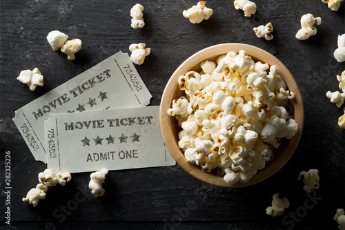 Movie tickets and bowl of popcorn on dark background. Home theatre movie or series night concept. Flat lay top view from above photo