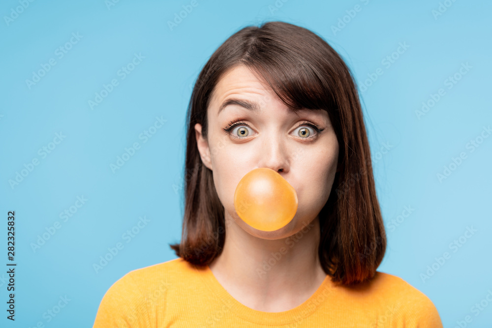 Young amazed brunette staring at you while blowing chewing-gum bubble Young amazed brunette staring at you while blowing chewing-gum bubble