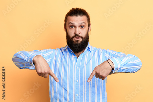 Фотография younghandsome man point with index fingers down, satisfied to advertise new obje