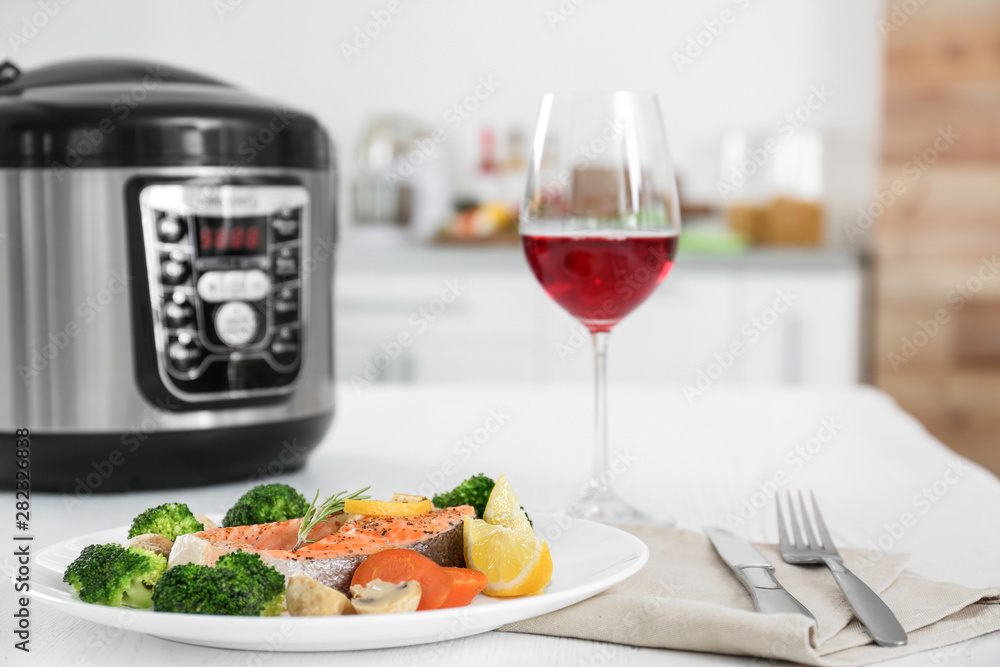 Plate with salmon steak and garnish prepared in multi cooker on table Plate with salmon steak and garnish prepared in multi cooker on table