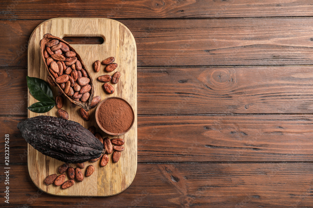 Board with cocoa pods, beans and powder on wooden table, top view with space for text Board with cocoa pods, beans and powder on wooden table, top view with space for text