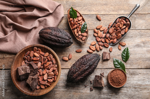 Kompozycja leżąca płasko z ziaren kakaowych, kawałków czekolady i strąków na drewnianym stole