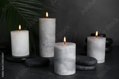 Burning candles and spa stones on black table