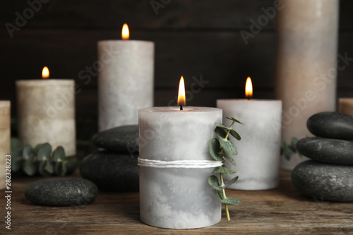 Composition with burning candles, spa stones and eucalyptus on wooden table