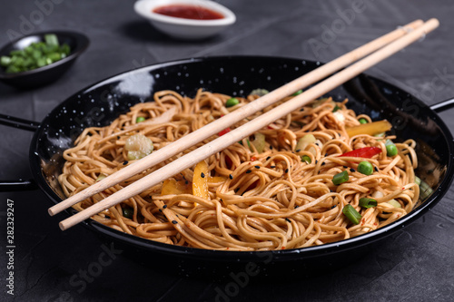 Cooked noodles with vegetables and chopsticks served on table