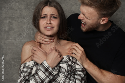 Cuadro en lienzo Man choking young woman on grey background. Stop sexual assault