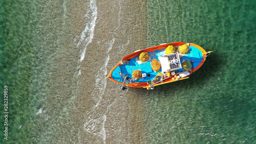Aerial drone top view of traditional fishing boat in small sand bar with turquoise sea, Aegean, Greece
