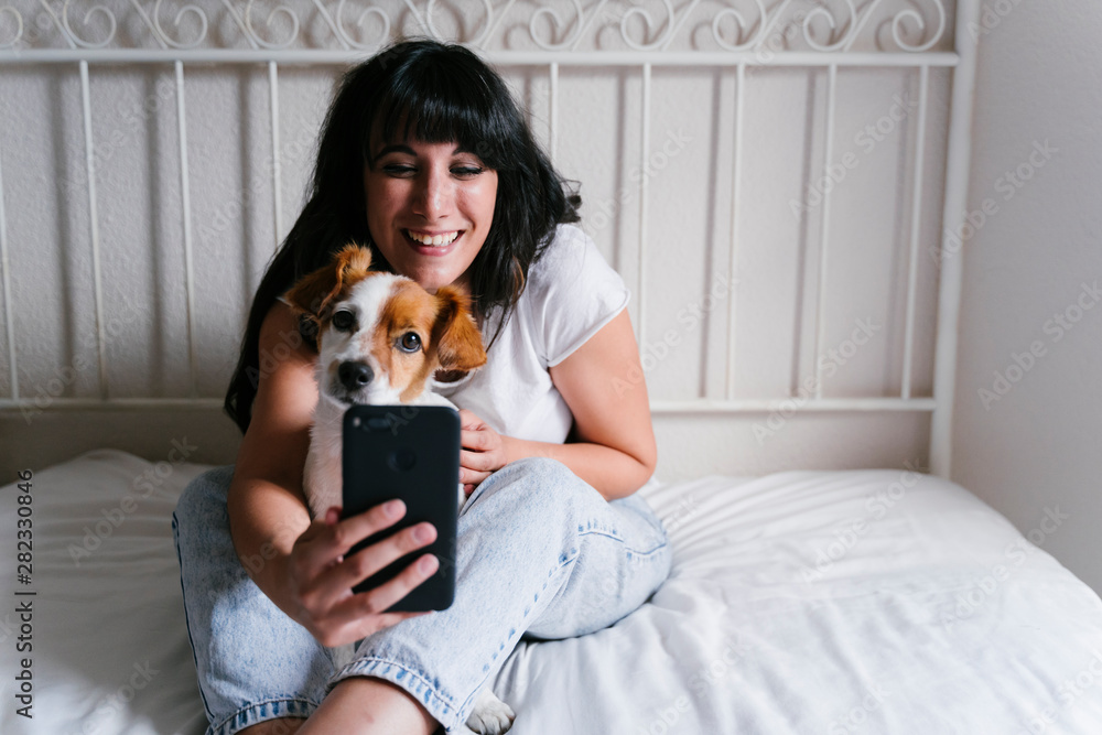 young caucasian woman on bed taking a selfie with mobile phone with her ...