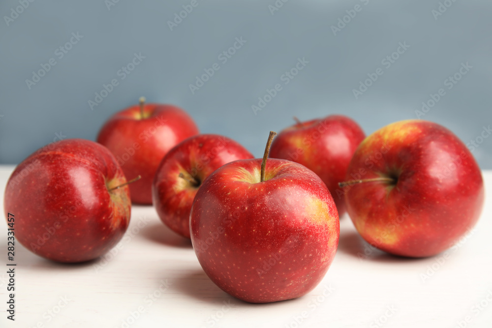 Ripe juicy red apples on white wooden table against blue background. Space for text Ripe juicy red apples on white wooden table against blue background. Space for text