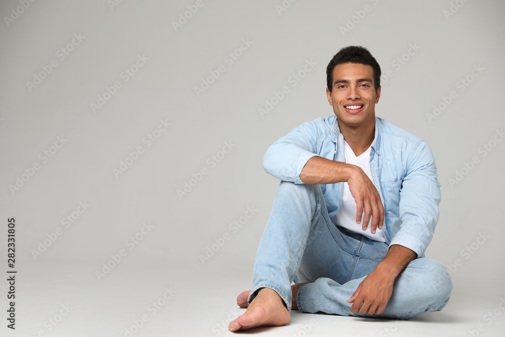 Handsome young African-American man sitting on light background. Space for text Handsome young African-American man sitting on light background. Space for text