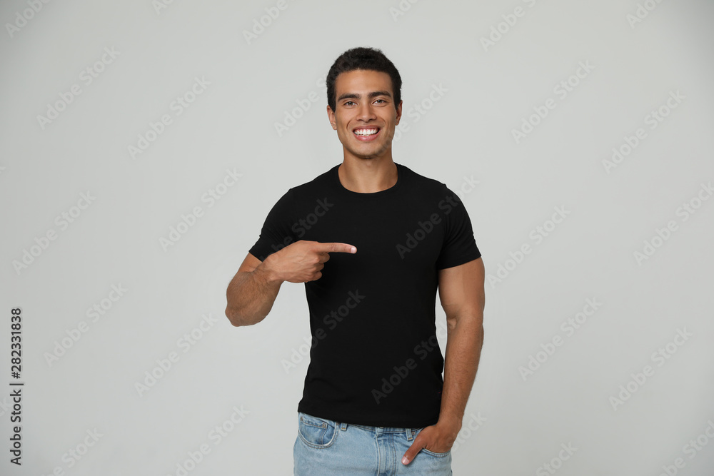 Handsome young African-American man in blank t-shirt on light background. Space for design Handsome young African-American man in blank t-shirt on light background. Space for design