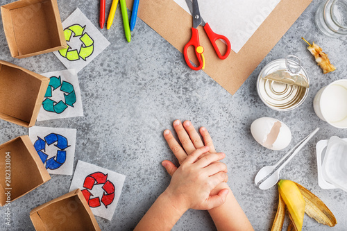 Girl hands are making recycling game in paper on grey background colourful